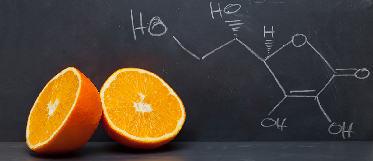picture of an sliced orange and the chemical structure of vitamin C drawn on a chalkboard