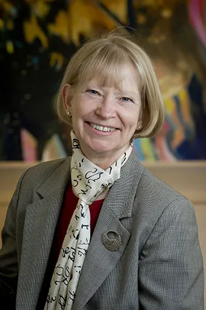 Dr. Maret Traber smiling at the camera in a gray blazer and scarf