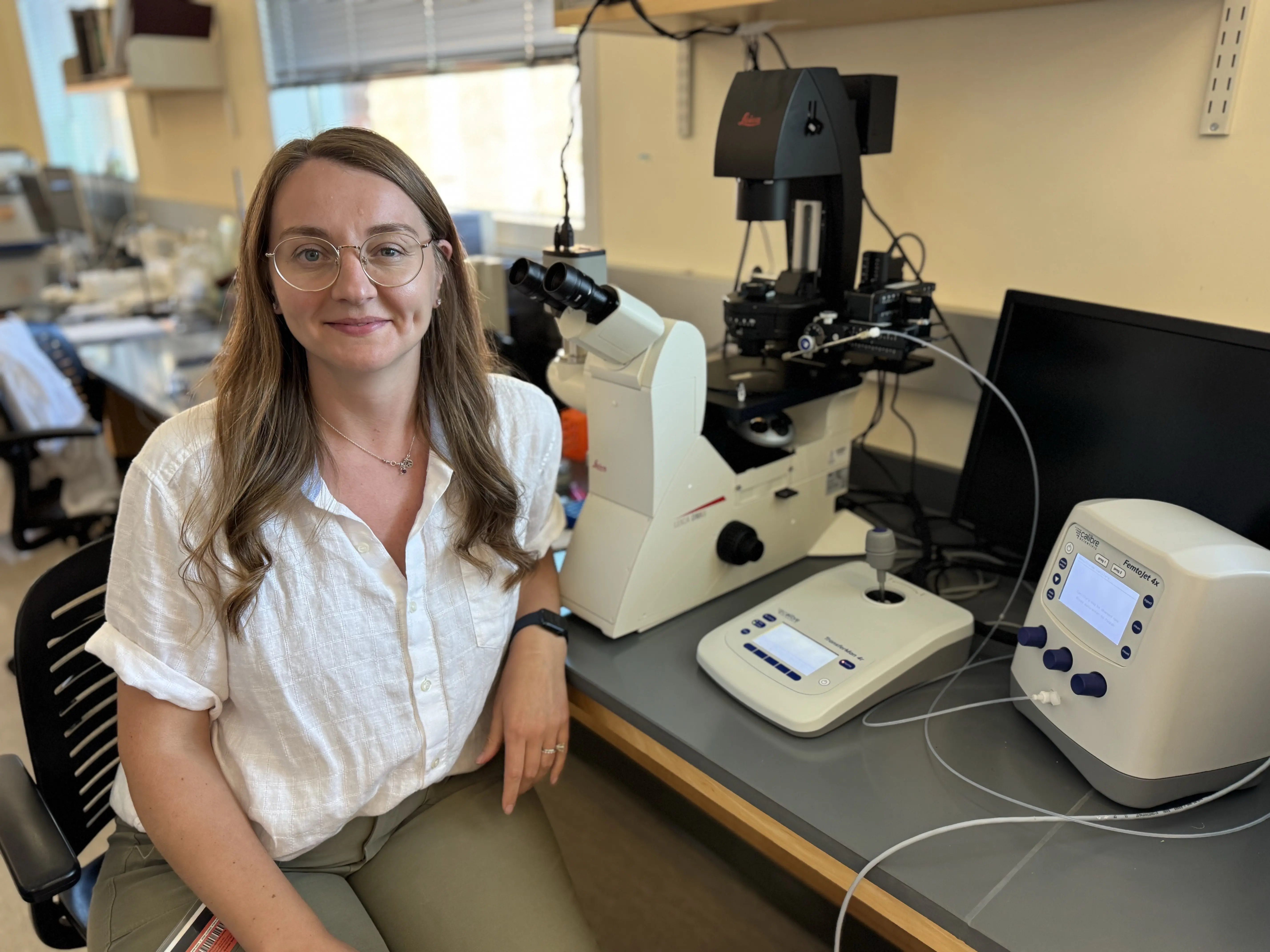 Dr. Maria Purce with a microscope and other lab equipment