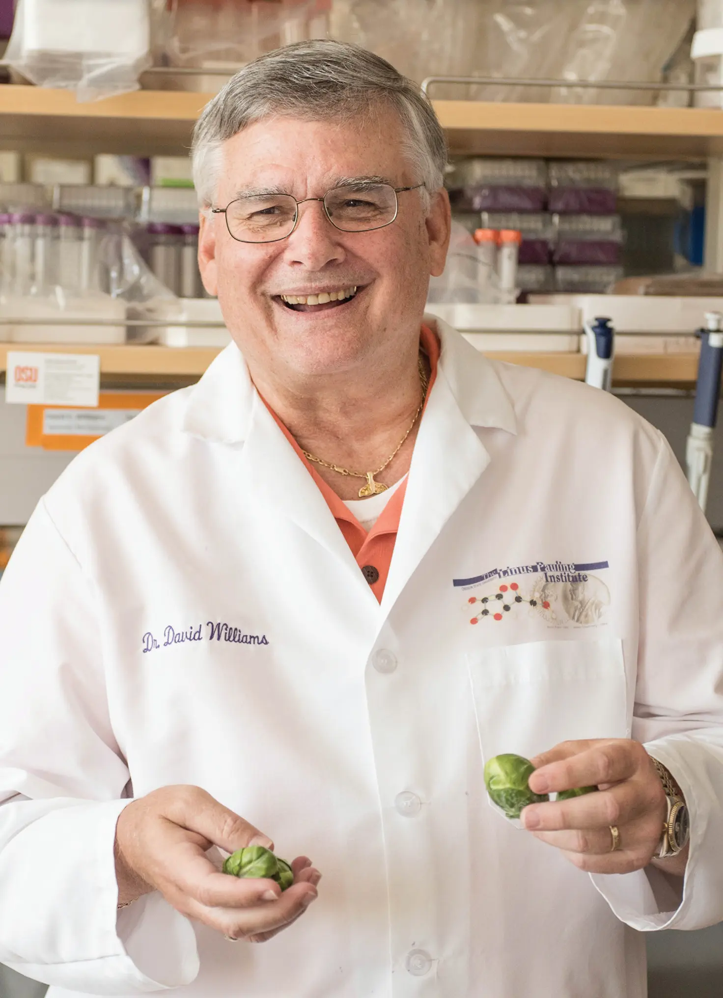 Dr. David Williams, wearing a white lab coat, holding Brussels sprouts and smiling